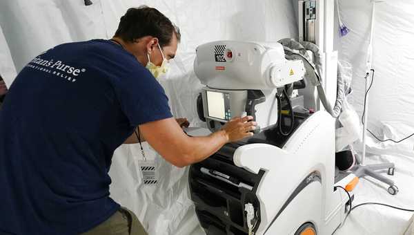 Joshua Verner, a nurse, makes adjustments on a portable X-Ray machine in one of four wards that are part of the 32-bed Samaritan's Purse Emergency Field Hospital set up in one of the University of Mississippi Medical Center's parking garages, Tuesday, Aug. 17, 2021, in Jackson, Miss. The field hospital was opened by the U.S. Department of Health and Human Services at UMMC in response to the rising number of COVID-19 cases in the state. (AP Photo/Rogelio V. Solis)