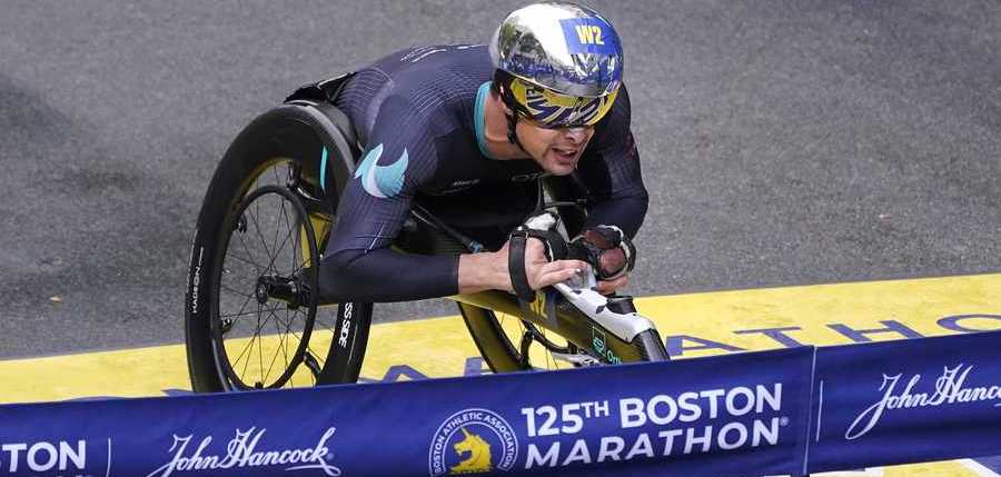 Marcel Hug, of Switzerland, rolls across the finish line to win the men's wheelchair division at the Boston Marathon in Boston, Monday, Oct. 11, 2021. (AP Photo/Charles Krupa)