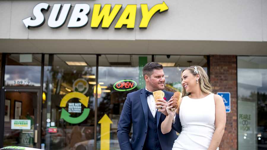 Julie and Zack Williams pose for a photo in a Subway sandwich-wrapped convertible outside of the Subway restaurant where they first met on Friday, Oct. 22, 2021 in Livonia, Mich. On their wedding day, the couple revisited the restaurant for a Subway-themed photo shoot.