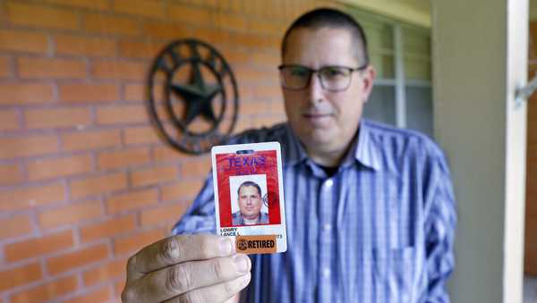 Lance Lowry, a recently retired corrections officer with the Texas State Penitentiary, holds his ID badge on the front porch of his home, Oct. 27, 2021, in Huntsville, Texas. Lowry, an officer for 20 years, became disheartened watching friends and coworkers die from COVID-19, along with dwindling support from his superiors. He left the prison system this summer for a job in long-haul trucking. (AP Photo/Michael Wyke)