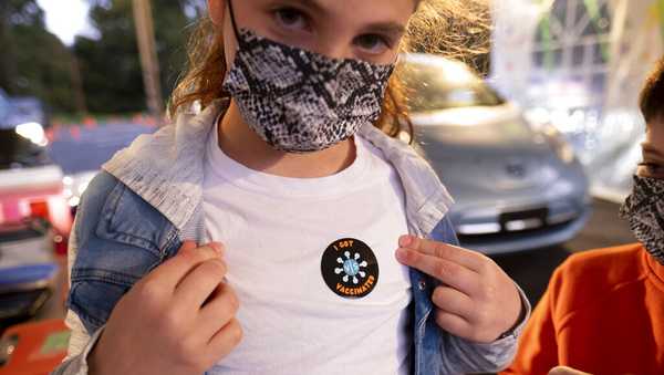 Leah Lefkove, 9, shows off her vaccination sticker just before being the first child to be vaccinated at the Viral Solutions vaccination and testing site in Decatur, Ga., on the first day COVID-19 vaccinations were available for children from 5 to 12 on Wednesday, Nov. 3, 2021. (AP Photo/Ben Gray)