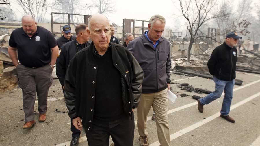 FILE - Former California Gov. Jerry Brown, center, and former Interior Secretary Ryan Zinke, second from right, tour the Camp-fire ravaged Paradise Elementary School in Paradise, Calif., on Nov. 14, 2018. Brown has called California&apos;s mega fires "the new abnormal" as climate change turns the state warmer and drier. With the help of Ken Pimlott, the former chief of the California Department of Forestry and Fire Protection, Brown convened a group at his rural Colusa County ranch in September 2021, to discuss what could be done to save California's forests. (AP Photo/Rich Pedroncelli, File)