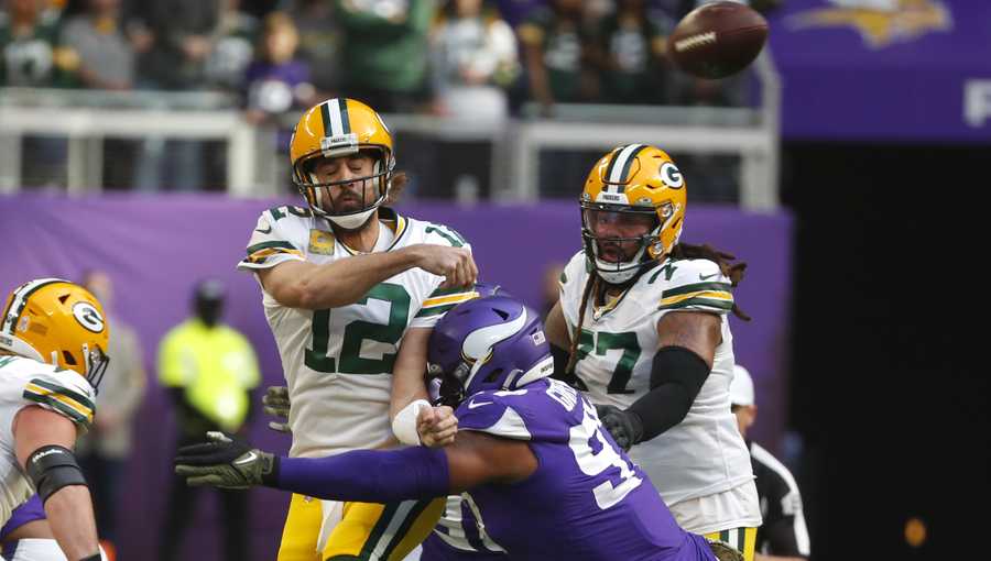 Green Bay Packers quarterback Aaron Rodgers (12) passes as he is hit by Minnesota Vikings defensive end Everson Griffen (97) during the first half of an NFL football game, Sunday, Nov. 21, 2021, in Minneapolis.