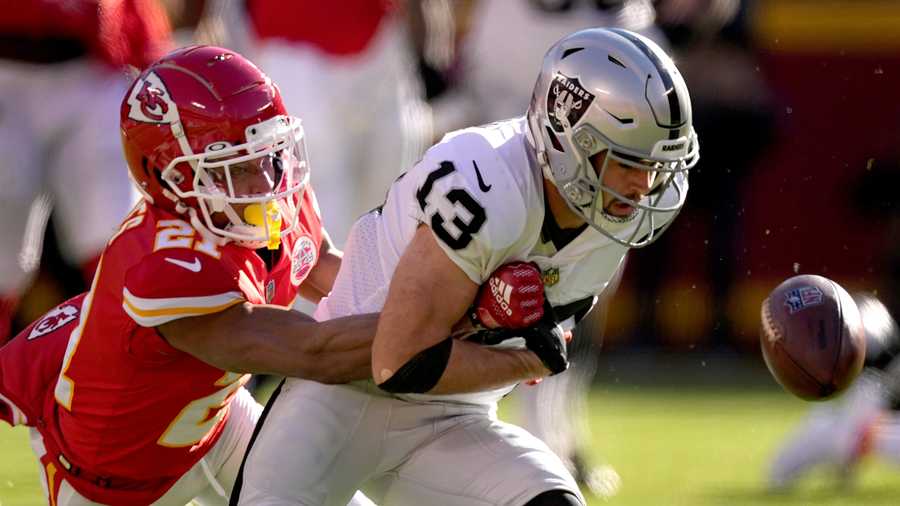 Las Vegas Raiders wide receiver Hunter Renfrow (13) fumbles the ball as he is hit by Kansas City Chiefs cornerback Mike Hughes (21) during the first half of an NFL football game Sunday, Dec. 12, 2021, in Kansas City, Mo. The Chiefs recovered the fumble. (AP Photo/Charlie Riedel)