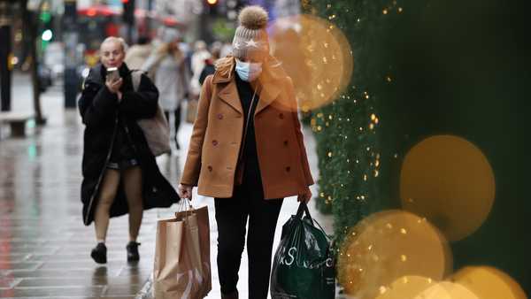 A woman wearing a face mask to guard against COVID-19 carries bags of shopping along Oxford Street in London, Monday, Dec. 27, 2021. In Britain, where the omicron variant has been dominant for days, government requirements have been largely voluntary and milder than those on the continent, but the Conservative government said it could impose new restrictions after Christmas. (AP Photo/David Cliff)