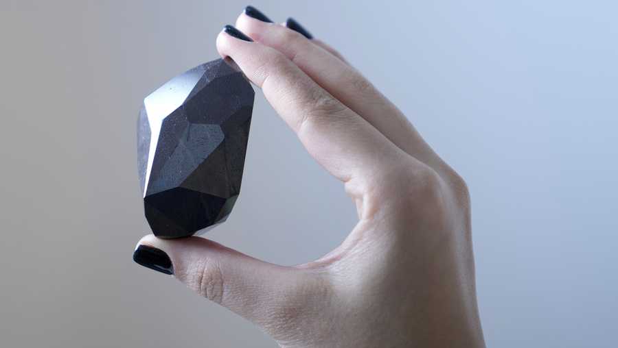 An employee presents a 555.55 Carat Black Diamond