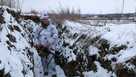 A serviceman stands holding his machine-gun in a trench on the territory controlled by pro-Russian militants at frontline with Ukrainian government forces in Slavyanoserbsk, Luhansk region, eastern Ukraine, Tuesday, Jan. 25, 2022.