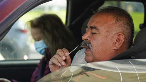 FILE - Jose Alfrtedo De la Cruz and his wife, Rogelia, self-test for COVID-19 at a no-cost COVID-19 drive-through event provided the GUARDaHEART Foundation for the City of Whittier community and the surrounding areas at the Guirado Park in Whittier, Calif., on Tuesday, Jan. 25, 2022. (AP Photo/Damian Dovarganes)