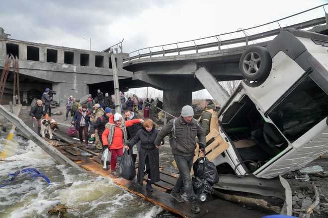 People&#x20;cross&#x20;an&#x20;improvised&#x20;path&#x20;under&#x20;a&#x20;destroyed&#x20;bridge&#x20;while&#x20;fleeing&#x20;the&#x20;town&#x20;of&#x20;Irpin&#x20;close&#x20;to&#x20;Kyiv,&#x20;Ukraine,&#x20;Monday,&#x20;March&#x20;7,&#x20;2022.