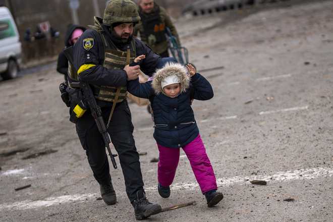 A&#x20;Ukrainian&#x20;police&#x20;officer&#x20;runs&#x20;while&#x20;holding&#x20;a&#x20;child&#x20;as&#x20;the&#x20;artillery&#x20;echoes&#x20;nearby,&#x20;while&#x20;fleeing&#x20;Irpin&#x20;on&#x20;the&#x20;outskirts&#x20;of&#x20;Kyiv,&#x20;Ukraine,&#x20;Monday,&#x20;March&#x20;7,&#x20;2022.