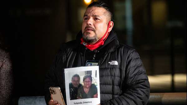 In a photo provided by Multnomah County, Adam Pena, a Multnomah County Aging and Disability Services employee who lost his mother, Yolanda Jimenez, to COVID-19 in 2021, holds a photo of his mother Thursday, March 10, 2022, in Portland, Ore., during an event held on the second anniversary of the first COVID-19 case in Portland. (Motoya Nakamura/Multnomah County via AP)