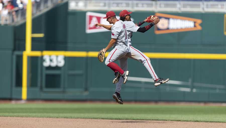 Arkansas infielders Robert Moore (1) and Jalen Battles (2) celebrate after their win over Stanford during an NCAA College World Series baseball game Saturday, June 18, 2022, in Omaha, Neb. (AP Photo/John Peterson)