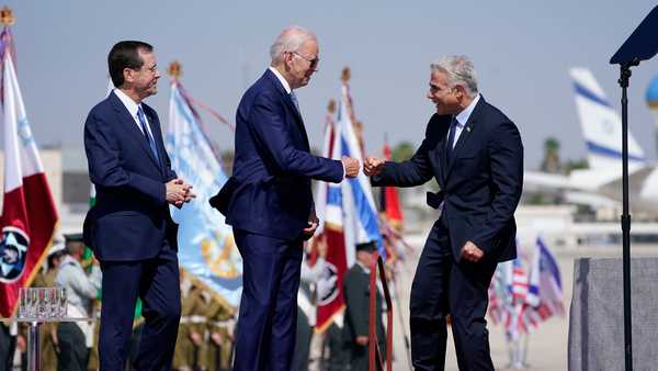 President Joe Biden fists bumps Israeli Prime Minister Yair Lapid, right, after arriving at Ben Gurion Airport, Wednesday, July 13, 2022, in Tel Aviv, as President Isaac Herzog, left, looks on. (AP Photo/Evan Vucci)