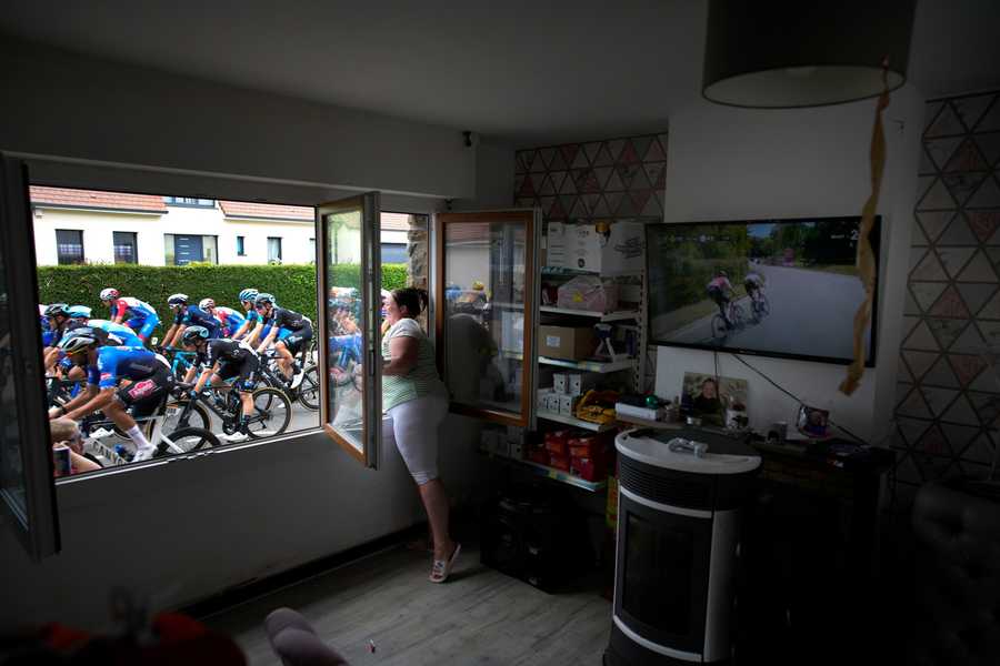 A woman cheers the riders, as she stands at her window, during the fourth stage of the Tour de France cycling race over 171.5 kilometers (106.6 miles) with start in Dunkerque and finish in Calais, France, Tuesday, July 5, 2022.