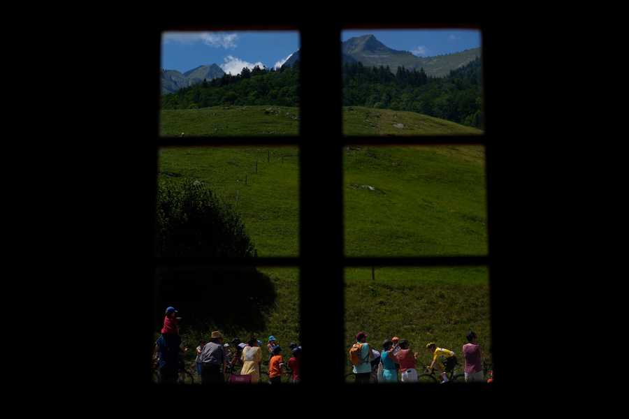 Spectators watch as the pack with Slovenia's Tadej Pogacar, wearing the overall leader's yellow jersey, bottom right, during the ninth stage of the Tour de France cycling race over 193 kilometers (119.9 miles) with start in Aigle, Switzerland and finish in Chatel les Portes du Soleil, France, Sunday, July 10, 2022.