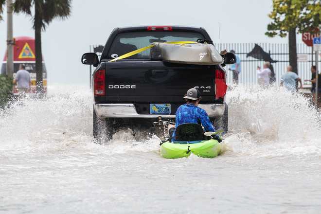 A truck and a man kayak on a low-lying road during flooding from Hurricane Ian, Wednesday afternoon, September 28, 2022.