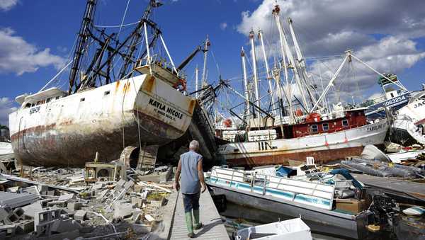 Bruce Hickey, 70, walks along the waterfront littered with debris, including shrimp boats, in the mobile home park where he and his wife Kathy have a winter home, a trailer originally purchased by Kathy's mother in 1979, on San Carlos Island, Fort Myers Beach, Fla., Wednesday, Oct. 5, 2022, one week after the passage of Hurricane Ian. (AP Photo/Rebecca Blackwell)