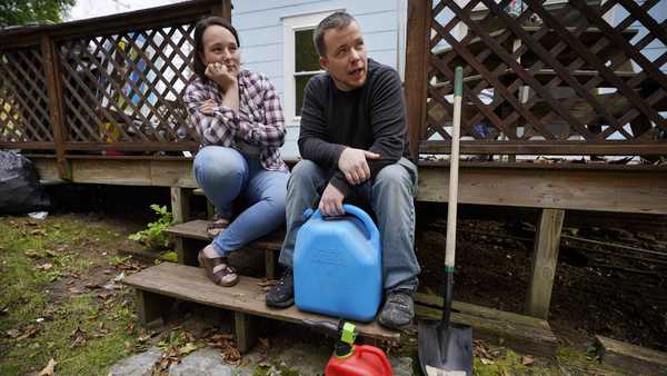 Lucinda Tyler and Aaron Raymo sit outside their home with fuel containers they used to fill their heating oil tank at their home, Wednesday, Oct. 5, 2022 in Jay, Maine. The couple shopped around for the best prices and bought heating oil 5 gallons at a time throughout the summer whenever they had any extra money.