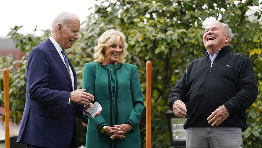 Dale Haney, the chief White House groundskeeper, right, laughs as he stands with President Joe Biden and first lady Jill Biden during a tree planting ceremony on the South Lawn of the White House, Monday, Oct. 24, 2022, in Washington. As of this month, Haney has tended the lawns and gardens of the White House for 50 years. (AP Photo/Evan Vucci)