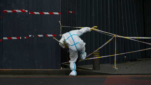 FILE - A worker in protective suit walks through the caution tapes along metal barricades retail shops that has been locked down as part of COVID-19 controls in Beijing, Sunday, June 26, 2022.