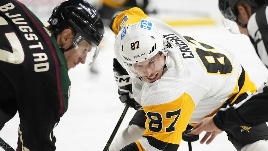 Pittsburgh Penguins center Sidney Crosby (87) watches the puck as linesman Trent Knorr, right, drops the puck on a face off against Arizona Coyotes center Nick Bjugstad, left, during the second period of an NHL hockey game in Tempe, Ariz., Sunday, Jan. 8, 2023.
