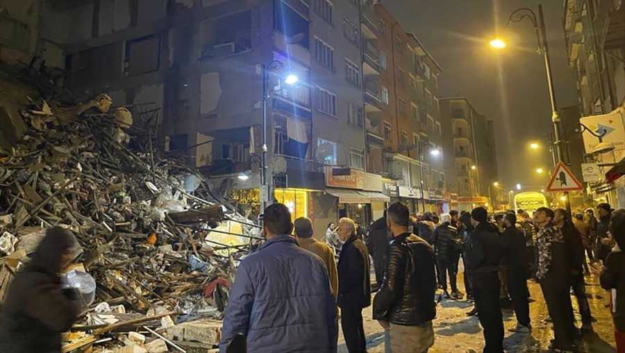 People gather around a collapsed building in Pazarcik, in Kahramanmaras province, southern Turkey, early Monday, Feb. 6, 2023. A powerful earthquake has caused significant damage in southeast Turkey and Syria and many casualties are feared. Damage was reported across several Turkish provinces, and rescue teams were being sent from around the country. (Depo Photos via AP)