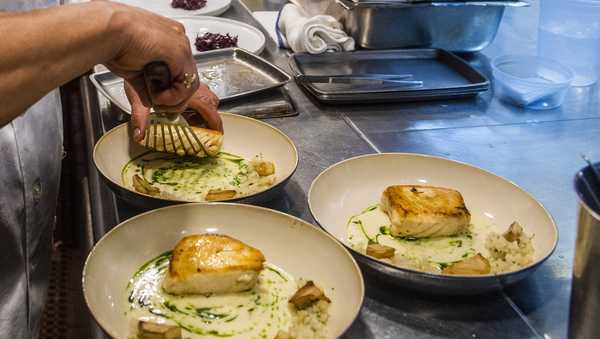 FILE - A worker arranges food onto plates in the kitchen of a restaurant in New York on Dec. 14, 2021. Food workers who showed up while sick or contagious were linked to about 40% of restaurant food poisoning outbreaks with a known cause between 2017 and 2019, federal health officials said Tuesday, May 30, 2023. (AP Photo/Brittainy Newman, File)