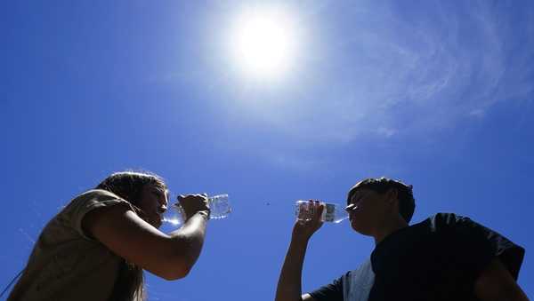Tony Berastegui Jr., 15, right, and his sister Giselle Berastegui, 12, drink water as temperatures are expected to hit 115-degrees, Monday, July 17, 2023, in Phoenix. (AP Photo/Ross D. Franklin)