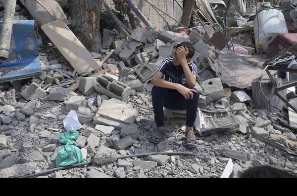 A Palestinian boy sits on the rubble of his building destroyed in an Israeli airstrike in Nuseirat camp in the central Gaza Strip on Monday, Oct. 16, 2023. (AP Photo/Hatem Moussa)