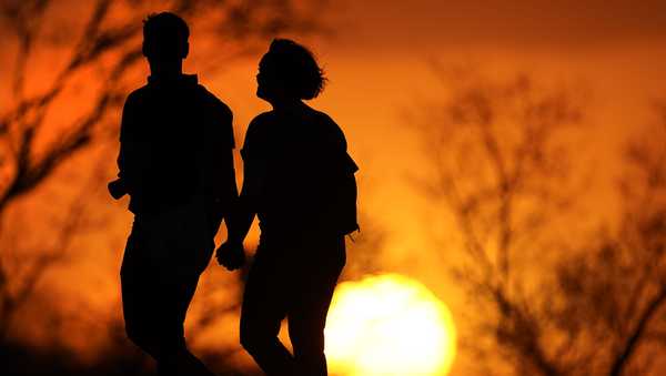 FILE - A couple walks through a park at sunset, March 10, 2021, in Kansas City, Mo. U.S. life expectancy rose in 2022 — by more than a year — after plunging two straight years at the beginning of the COVID-19 pandemic, according to a new government report released Wednesday, Nov. 29, 2023. The rise was mainly due to the waning of the pandemic in 2022, researchers said at the Centers for Disease Control and Prevention. (AP Photo/Charlie Riedel, File)