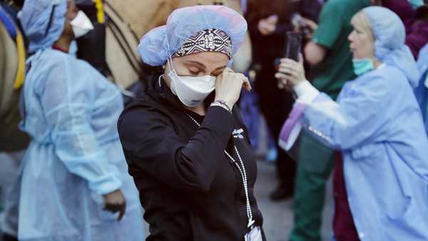 A medical worker reacts as police officers and pedestrians cheer medical workers outside NYU Medical Center in New York, April 16, 2020.