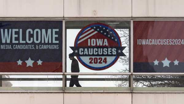 A man walks past a sign that reads "Iowa Caucuses 2024" in downtown Des Moines, Iowa, Saturday, Jan. 13, 2024. (AP Photo/Andrew Harnik)