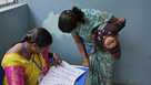 FILE - A woman checks for her name before casting her vote at a polling station during the Telangana state assembly elections in Hyderabad, India, Nov. 30, 2023.
