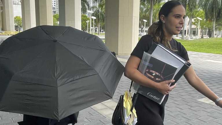 Celebrity handbag designer Nancy Gonzalez hides under an umbrella as she walks with her lawyer Andrea Lopez outside the federal courthouse Monday, April 22, 2024, in Miami. The Colombian designer, whose bags were purchased by celebrities like Britney Spears and the cast of the &quot;Sex and the City&quot; TV series, was sentenced to 18 months in federal prison on Monday for leading a smuggling ring that illegally imported into the U.S. crocodile handbags for sale at high end showrooms using couriers on commercial flights. (AP Photo/Josh Goodman)