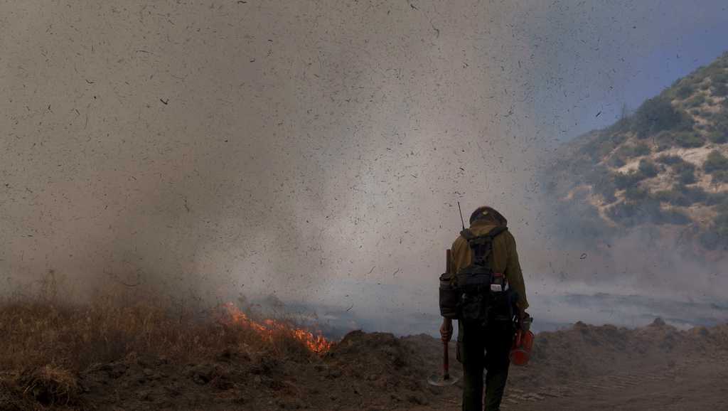 Sweltering Condition Crews working in sweltering conditions and steep terrain battle major ...