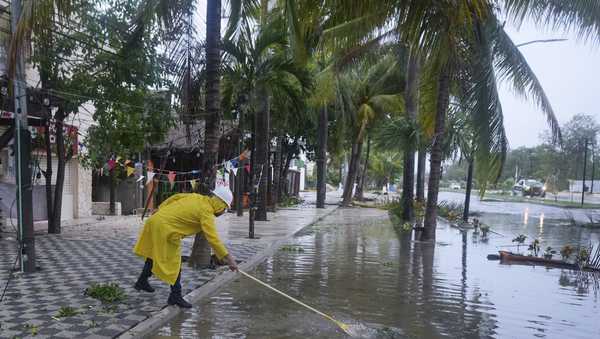 A man unclogs a drain in the aftermath of Hurricane Beryl, in Tulum, Mexico, Friday, July 5, 2024. (AP Photo/Fernando Llano)