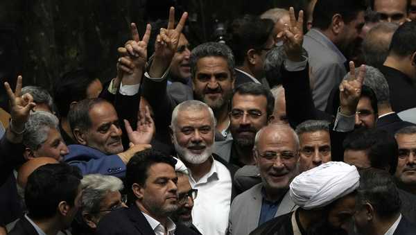 Palestinian Hamas chief Ismail Haniyeh, center, flashes a victory sign as he is surrounded by a group of Iranian lawmakers after the conclusion of the swearing-in ceremony of newly-elected Iranian President Masoud Pezeshkian at the parliament in Tehran, Iran, Tuesday, 30, 2024.