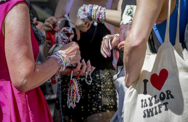 Swifties trade bracelets in the city centre in Vienna on Thursday, Aug.8, 2024. Organizers of three Taylor Swift concerts in the stadium in Vienna this week called them off on Wednesday after officials announced arrests over an apparent plot to launch an attack on an event in the Vienna area such as the concerts. (AP Photo/Heinz-Peter Bader)