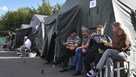 People evacuated from a fighting between Russian and Ukrainian forces in Kursk region sit next to tents at a temporary residence center in Kursk, Russia, Monday, Aug. 12, 2024.