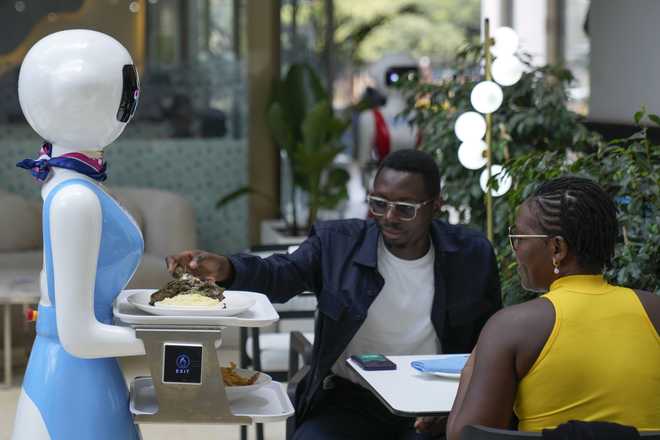 Robotic&#x20;waiter&#x20;Claire,&#x20;delivers&#x20;an&#x20;order&#x20;to&#x20;customers&#x20;at&#x20;the&#x20;Robot&#x20;Cafe&#x20;in&#x20;Nairobi,&#x20;Kenya&#x20;Thursday,&#x20;Aug.&#x20;29,&#x20;2024.&#x20;The&#x20;three&#x20;robots,&#x20;christened&#x20;Claire,&#x20;R24&#x20;and&#x20;Nadia,&#x20;are&#x20;not&#x20;programmed&#x20;to&#x20;have&#x20;a&#x20;full&#x20;conversation&#x20;with&#x20;customers,&#x20;but&#x20;they&#x20;can&#x20;say&#x20;&quot;Your&#x20;order&#x20;is&#x20;ready,&#x20;Welcome,&quot;&#x20;then&#x20;people&#x20;have&#x20;to&#x20;press&#x20;an&#x20;exit&#x20;button&#x20;after&#x20;picking&#x20;up&#x20;their&#x20;food&#x20;from&#x20;the&#x20;tray.