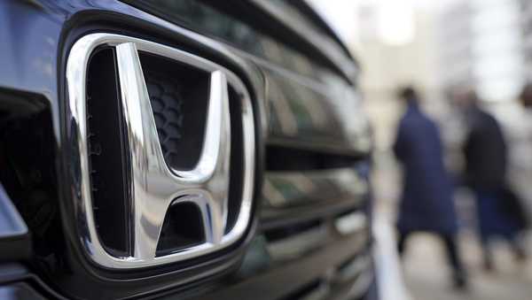 FILE - People walk near the logo of Honda Motor Company at a showroom on Feb. 8, 2022, in Tokyo. (AP Photo/Eugene Hoshiko, File)