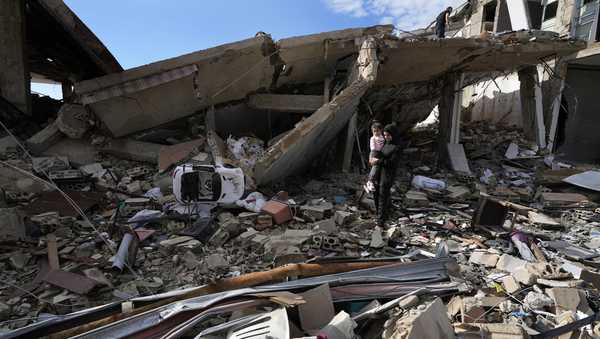 Safaa Haidous, carries her daughter Yara, 4, while walking on the rubble of her parents destroyed house after she returned to Hanouiyeh village, southern Lebanon, Thursday, Nov. 28, 2024 following a ceasefire between Israel and Hezbollah that went into effect on Wednesday.(AP Photo/Hussein Malla)