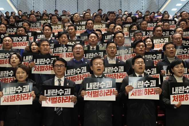 South Korea&apos;s main opposition Democratic Party leader Lee Jae-myung, bottom center, shout slogans during a press conference with his party members at the National Assembly in Seoul, South Korea, Saturday, Dec. 7, 2024. The signs read &quot;Punish the rebellion leader.&quot; (AP Photo/Ahn Young-joon)