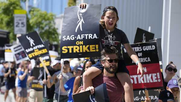 FILE - Director of Photography Jac Cheairs and his son, actor Wyatt Cheairs, 11, take part in a rally by striking writers and actors outside Netflix studio in Los Angeles on Friday, July 14, 2023. (AP Photo/Chris Pizzello, File)