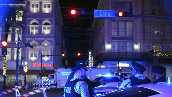 Police officers stand near the scene where a vehicle drove into a crowd on New Orleans' Canal and Bourbon streets, Wednesday, Jan. 1, 2025.