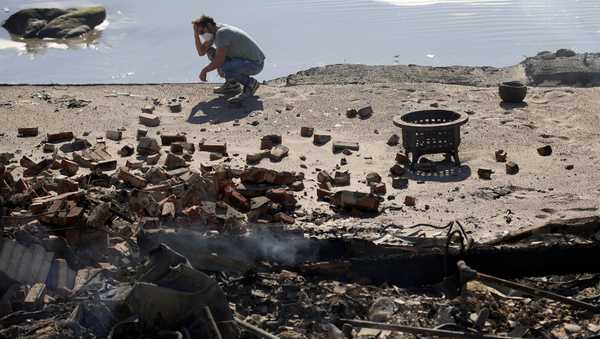 Luke Dexter kneels in front of his father's fire-ravaged beach front property in the aftermath of the Palisades Fire Friday, Jan. 10, 2025 in Malibu, Calif. (AP Photo/John Locher)