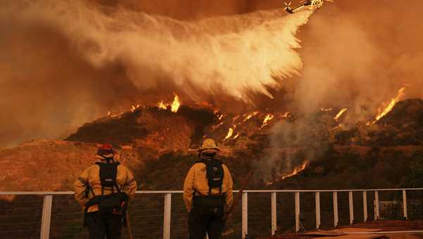 Firefighters watch as water is dropped on the Palisades Fire in Mandeville Canyon Saturday, Jan. 11, 2025, in Los Angeles. (AP Photo/Jae C. Hong)