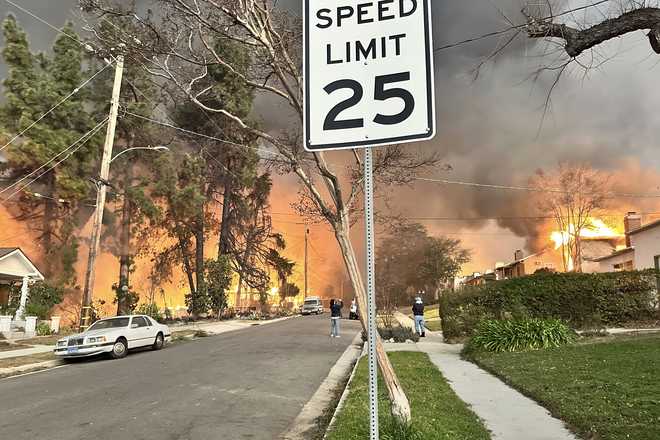 The Eaton Fire burns homes as Ryan Pearson, a Los Angeles-based entertainment video editor for The Associated Press, drives through his neighborhood in Altadena, California, Wednesday, Jan. 8, 2025.