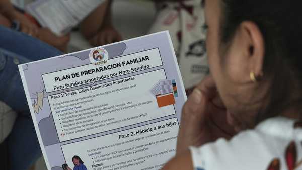 A mother reads a pamphlet to help her family prepare in the event she is apprehended by immigration authorities, Sunday, Jan. 19, 2025, in Miami. (AP Photo/Marta Lavandier)