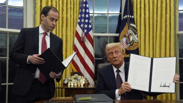 President Donald Trump holds up an executive order commuting sentences for people convicted of Jan. 6 offenses in the Oval Office of the White House, Monday, Jan. 20, 2025, in Washington.